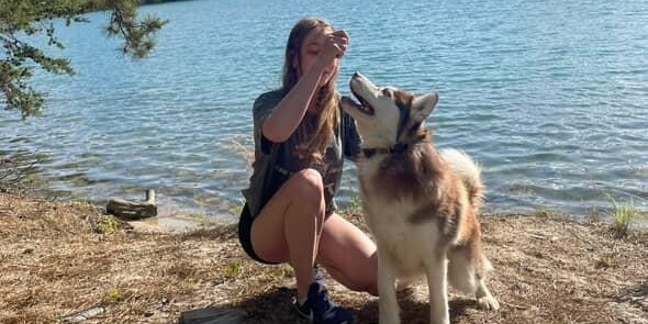Samantha giving a cue to a husky by the lake, working through distractions