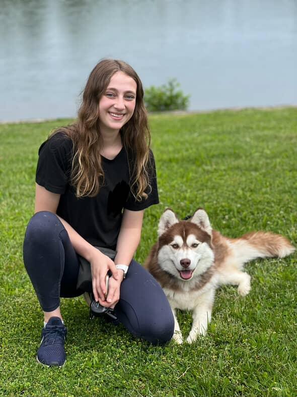 Samantha kneeling with Bueller by the lake